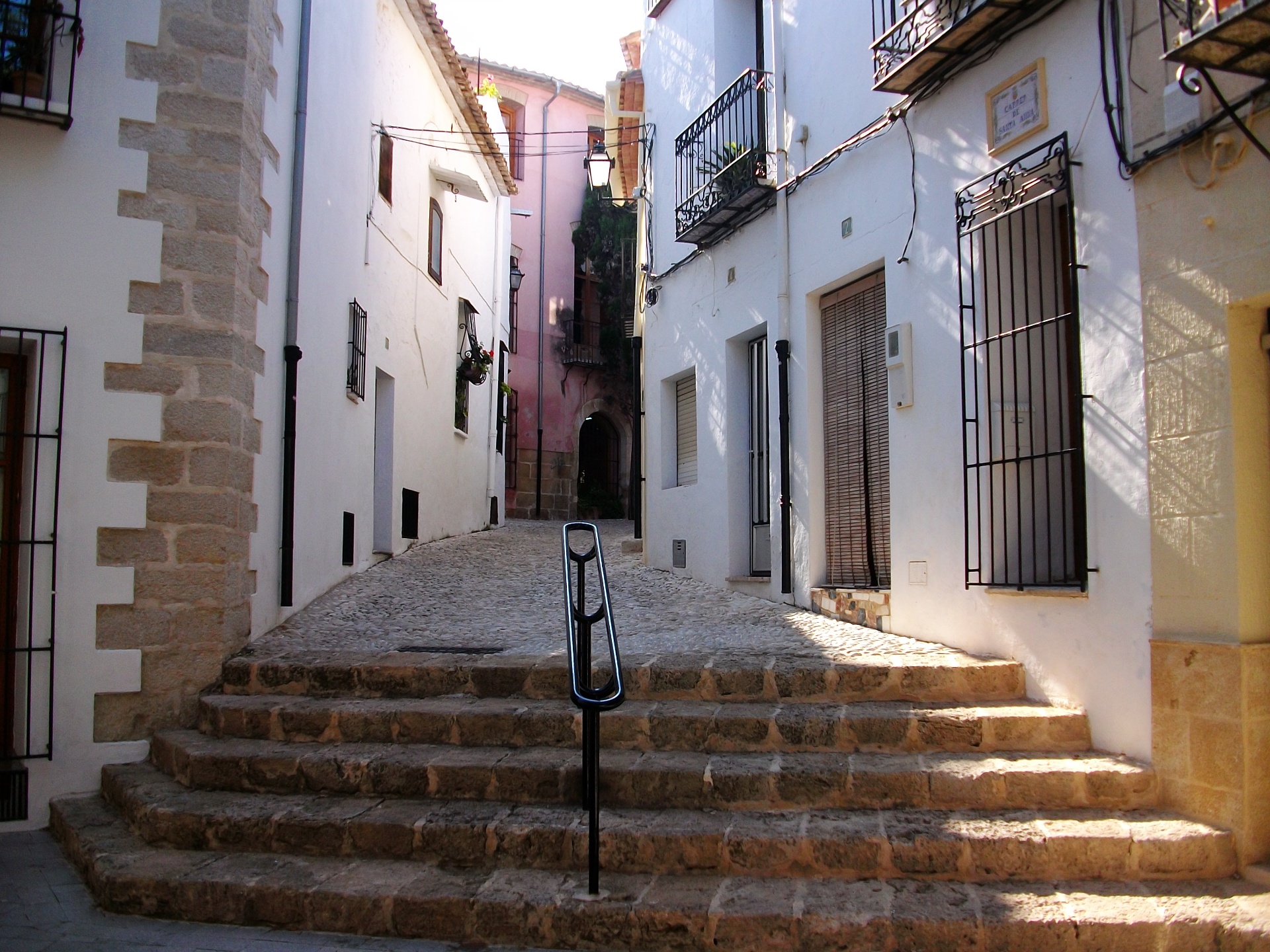 Carrer de Santa Anna en el casco antiguo de Benissa: calle estrecha de piedra con balcones de forja